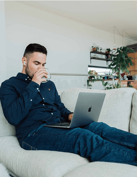 男性がソファーの上でパソコンの作業をしている画像