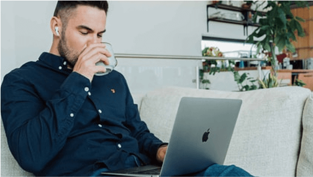 男性がソファーの上でパソコンの作業をしている画像